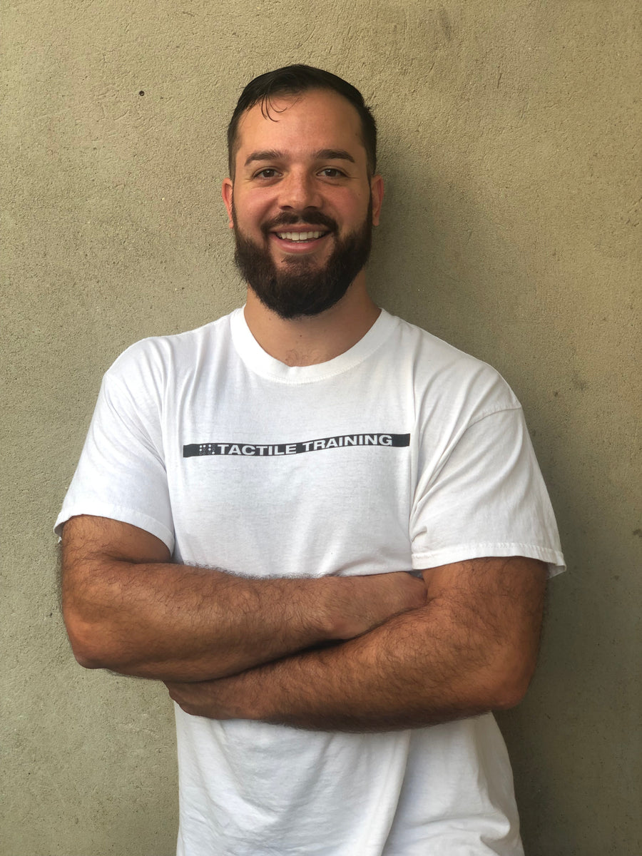 Image of Coach Brandon smiling with arms folded wearing a T-Shirt that says Tactile Training